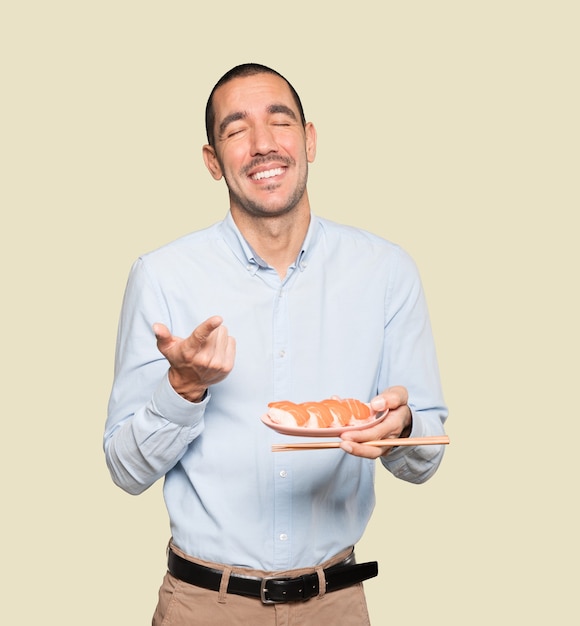 Jeune homme à l'aide de baguettes pour manger des sushis