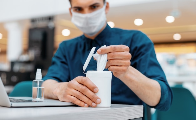 jeune homme à l'aide de lingettes antiseptiques sur le lieu de travail