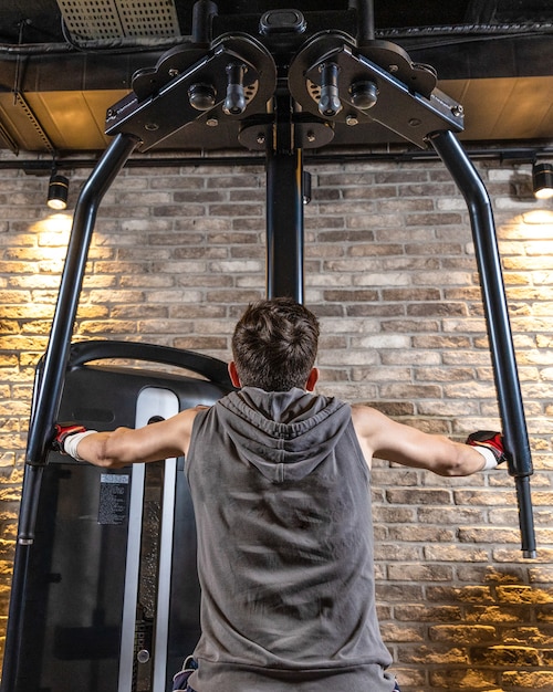 Jeune homme à l'aide de machine fly pec deck vue arrière