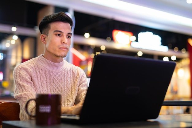 Jeune homme à l'aide d'un ordinateur portable au café