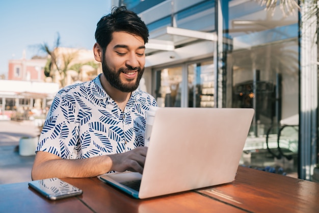 Jeune homme à l'aide de son ordinateur portable dans un café.