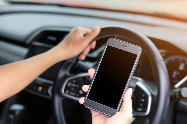 Jeune homme à l&#39;aide de téléphone en conduisant la voiture