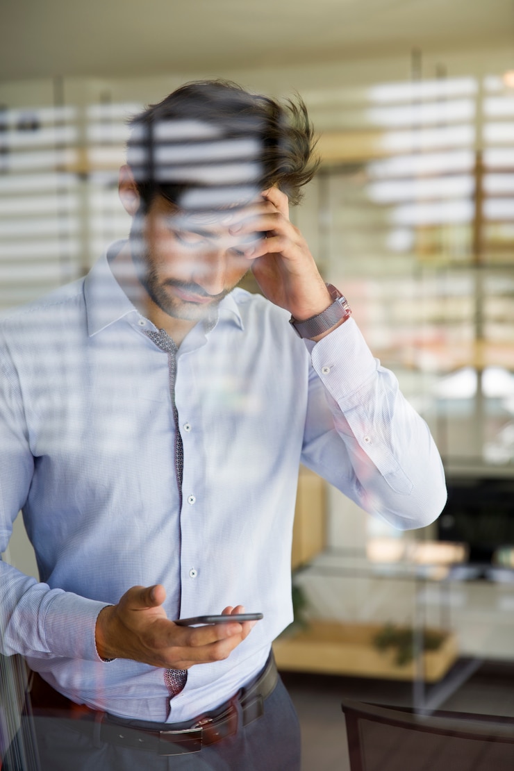 Photo jeune homme à l'aide d'un téléphone portable derrière la vitre au bureau