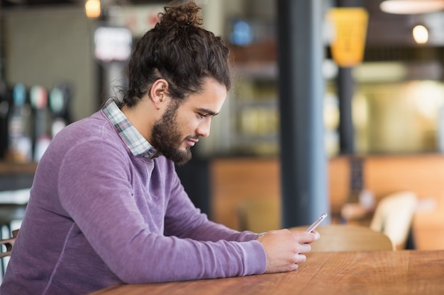 Jeune homme à l'aide de téléphones mobiles au restaurant