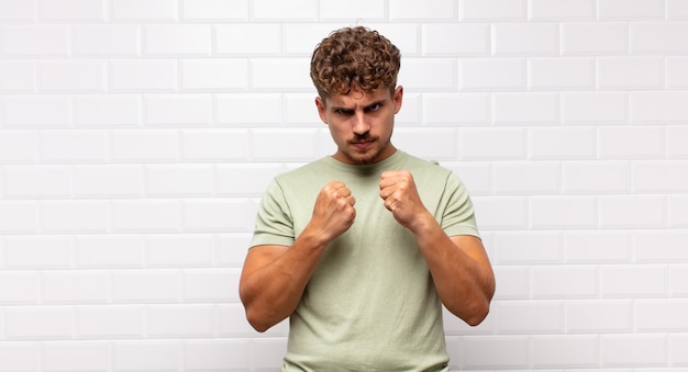 Jeune homme à l'air confiant, en colère, fort et agressif, avec les poings prêts à se battre en position de boxe