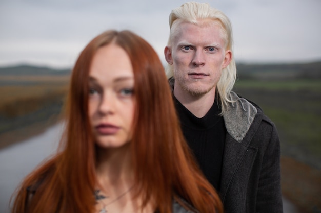 Jeune homme albinos et fille rousse se tiennent sur une route de campagne