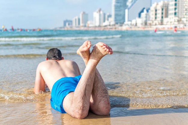 Jeune homme allongé sur la plage