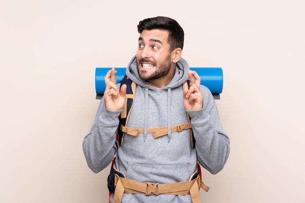 Jeune homme alpiniste avec un grand sac à dos avec les doigts qui se croisent