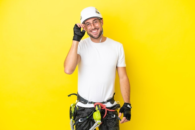 Jeune homme d'alpiniste isolé sur fond jaune avec des lunettes et heureux