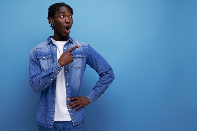 Un jeune homme américain élégant et surpris avec des dreadlocks avec une idée brillante se montre sur le côté