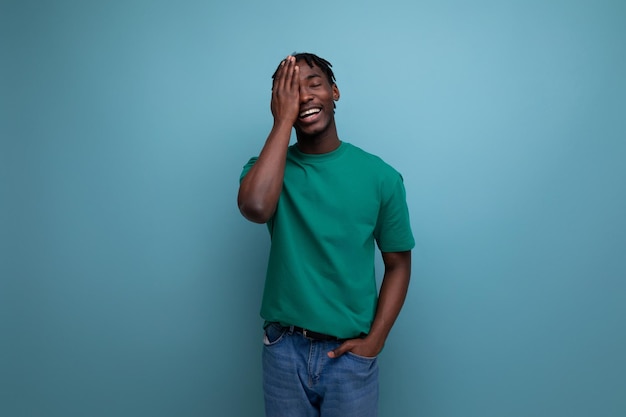 Jeune homme américain positif avec des dreadlocks en t-shirt vert décontracté sur fond avec espace de copie