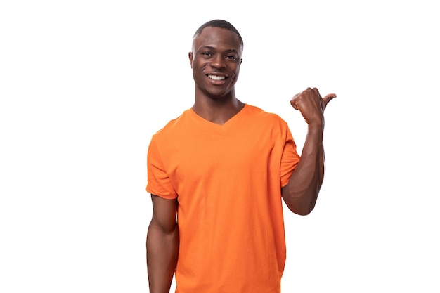 Jeune homme américain vêtu d'un t-shirt orange avec une maquette imprimée pointant du doigt les nouvelles