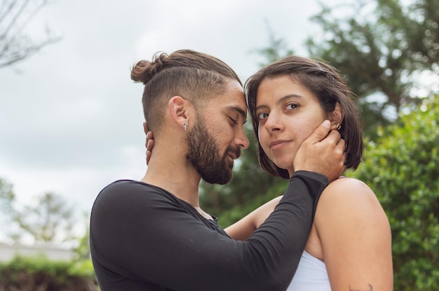 Jeune homme amoureux touchant le visage de sa bien-aimée avec les yeux fermés pendant qu'elle regarde la caméra