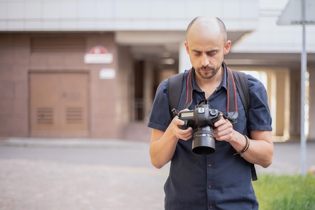 Jeune homme avec un appareil photo debout sur une rue de la ville