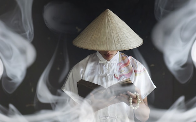 Le jeune homme d'apparence asiatique dans un kimono prie avec un livre