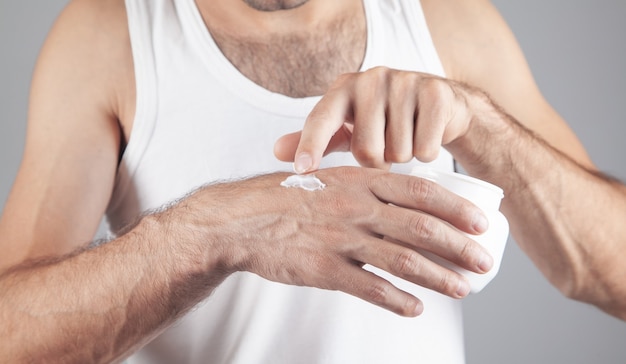 Jeune homme appliquant la crème dans les mains.