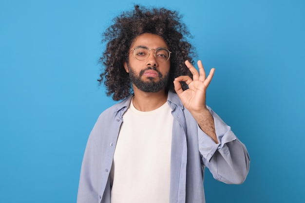 Photo un jeune homme arabe arrogant et sûr de lui montre un panneau ok en studio