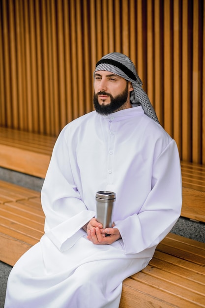 Jeune homme arabe assis sur un banc en bois avec du métal