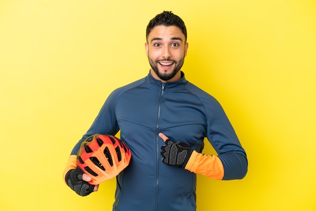 Jeune homme arabe cycliste isolé sur fond jaune avec une expression faciale surprise