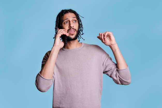 Jeune homme arabe discutant sur un téléphone portable tout en expliquant ses pensées et en gesticulant avec les mains. Belle personne en vêtements décontractés répondant à un appel, ayant une conversation sur smartphone