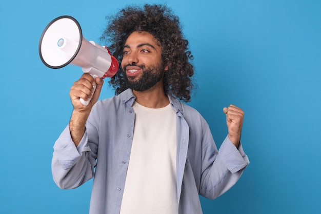 Photo jeune homme arabe fait un geste de victoire et tient un mégaphone dans le studio