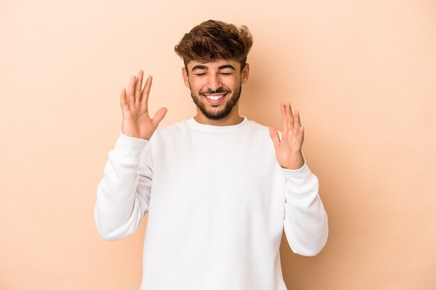 Jeune homme arabe isolé sur fond beige joyeux riant beaucoup. Notion de bonheur.