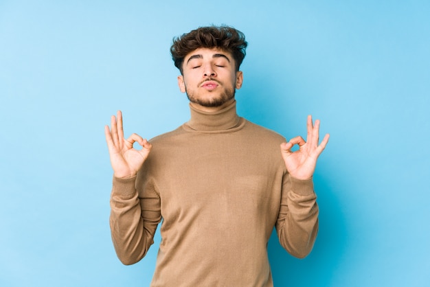 Jeune homme arabe isolé se détend après une dure journée de travail, elle effectue du yoga.