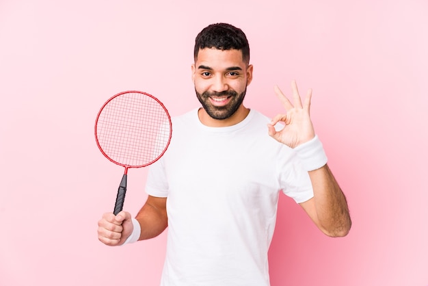 Jeune homme arabe jouant au badminton isolé gai et confiant montrant le geste ok.