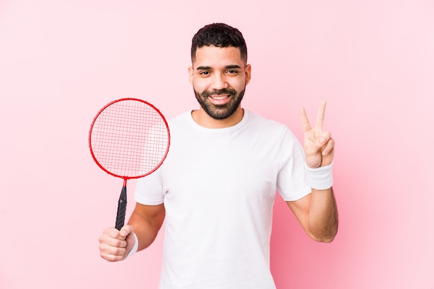 Jeune homme arabe jouant au badminton montrant le numéro deux avec les doigts.