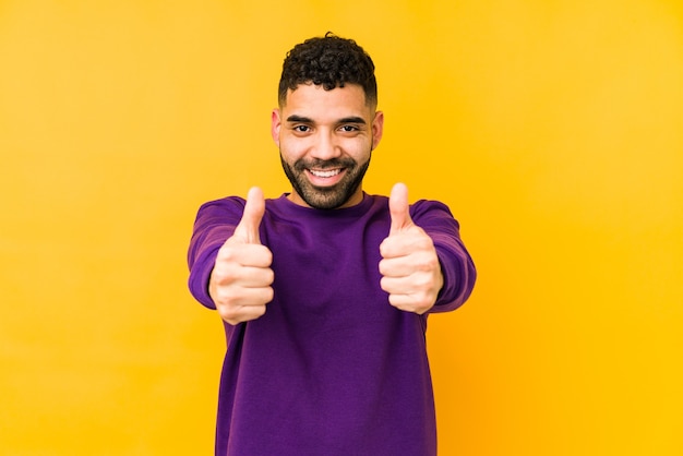 Jeune homme arabe métisse isolé avec des pouces vers le haut, applaudit quelque chose, concept de soutien et de respect.