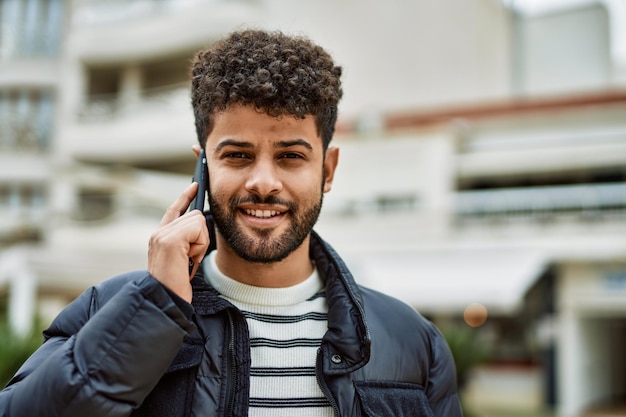 Jeune homme arabe parlant au téléphone à l'extérieur de la ville