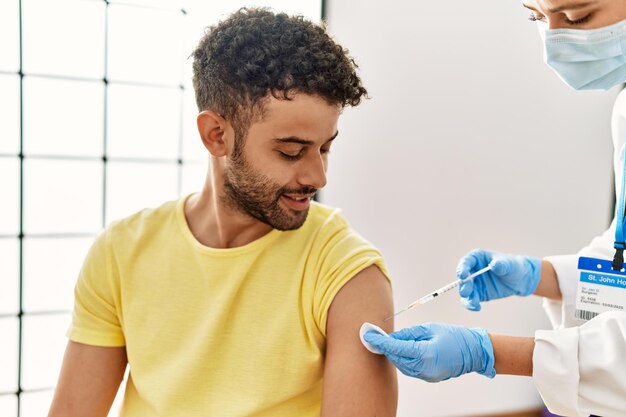 Photo jeune homme arabe souriant heureux en attendant le vaccin covid19 à l'hôpital