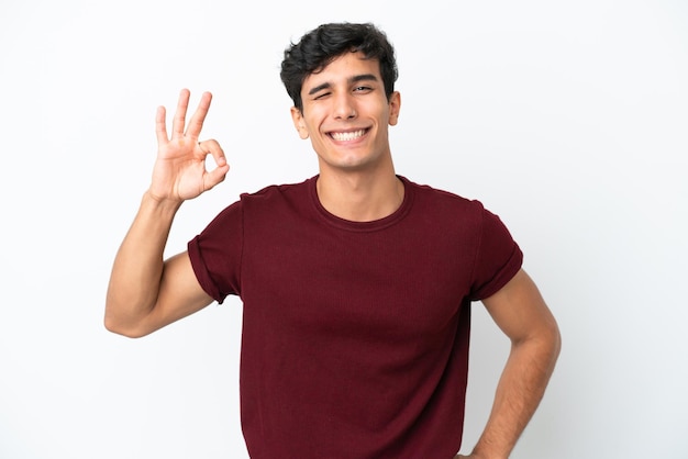 Jeune homme argentin isolé sur fond blanc montrant signe ok avec les doigts