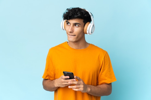 Jeune Homme Argentin Isolé Sur Le Mur à L'écoute De La Musique Avec Un Mobile Et De La Pensée