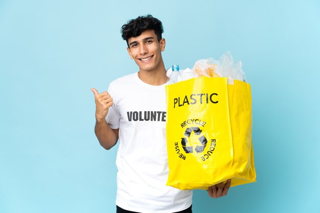 Jeune homme argentin tenant un sac plein de plastique pointant vers le côté pour présenter un produit