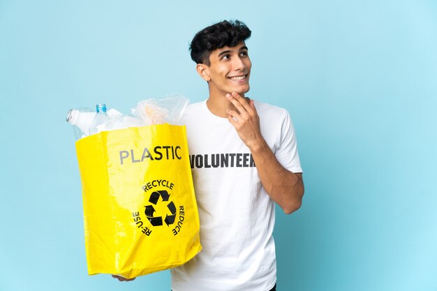 Jeune homme argentin tenant un sac plein de plastique à la recherche en souriant