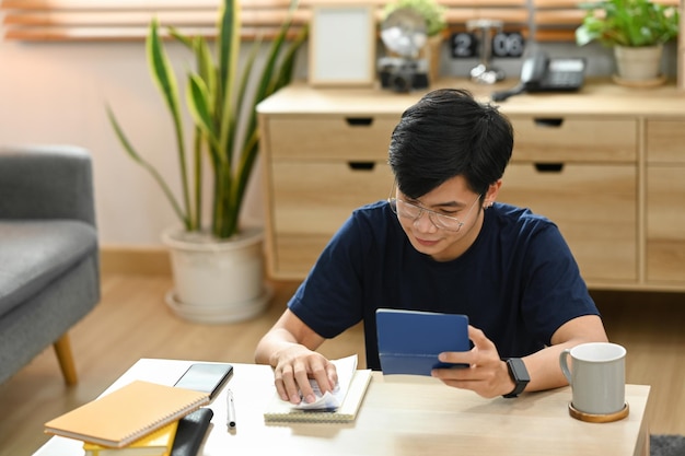 Jeune homme asiatique à l'aide d'une calculatrice pour calculer les paiements de loyer de prêt de banque d'argent gérer les finances des dépenses