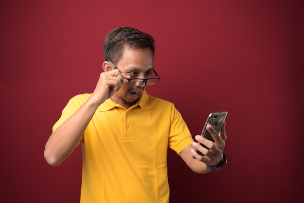 Le jeune homme asiatique a l'air surpris des bonnes nouvelles qu'il a reçues de son smartphone.