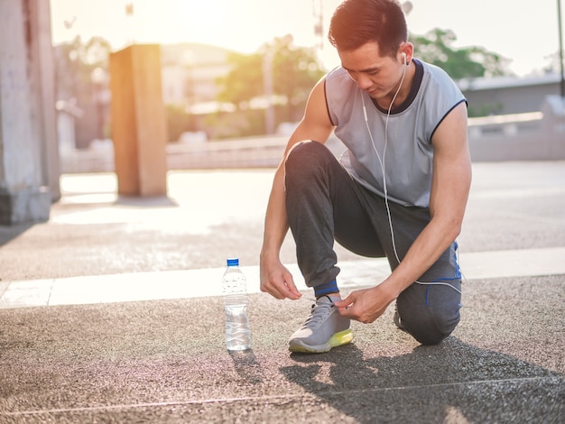 Jeune homme asiatique, attachant des chaussures de jogging, concept de mode de vie sain.