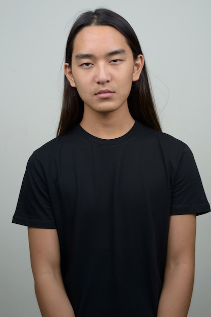 Jeune homme asiatique aux cheveux longs regardant la caméra