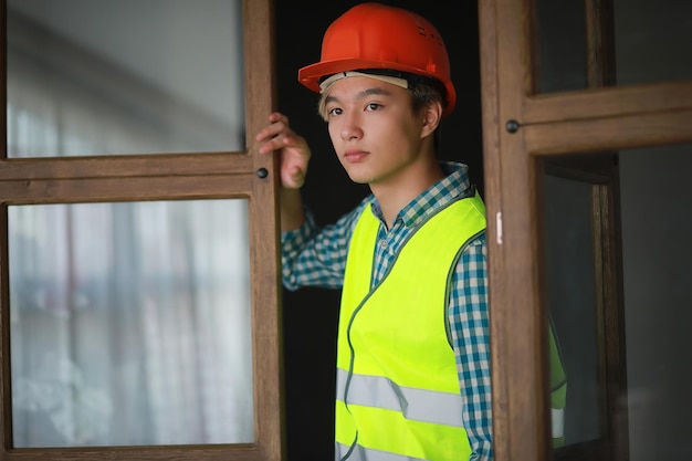 Jeune homme asiatique en casque de protection et gilet de construction