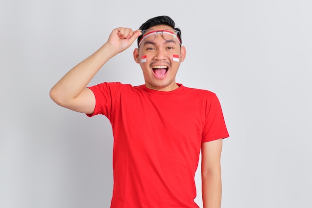 Un jeune homme asiatique choqué célébrant la fête de l'indépendance indonésienne enlève des lunettes isolées sur fond blanc