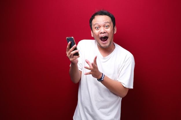 Jeune homme asiatique choqué quand il regarde et pointe un smartphone
