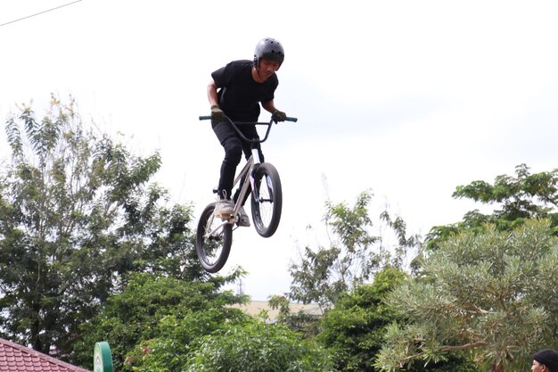 Jeune homme asiatique démontrant quelques tours de freestyle BMX dans les airs.