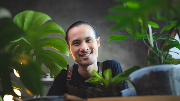 Un jeune homme asiatique est heureux de cultiver des plantes dans un petit jardin vert à la maison, d'un mode de vie amateur avec une nature verte dans une maison, d'un arbre à fleurs en pot à la culture de l'agriculture du jardinage botanique