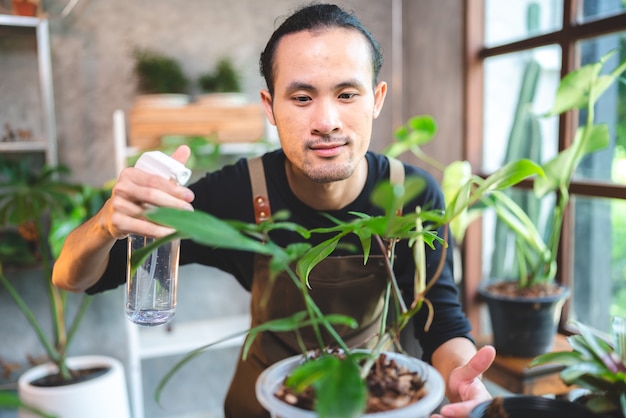 Un jeune homme asiatique est heureux de cultiver des plantes dans un petit jardin vert à la maison, d'un mode de vie amateur avec une nature verte dans une maison, d'un arbre à fleurs en pot à la culture de l'agriculture du jardinage botanique