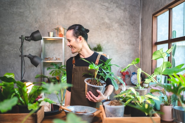 Un jeune homme asiatique est heureux de cultiver des plantes dans un petit jardin vert à la maison, d'un mode de vie amateur avec une nature verte dans une maison, d'un arbre à fleurs en pot à la culture de l'agriculture du jardinage botanique