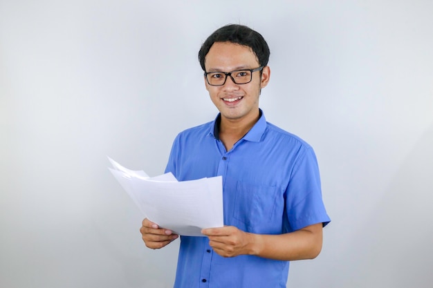 Jeune homme asiatique est souriant et heureux en regardant sur un document papier Homme indonésien portant une chemise bleue