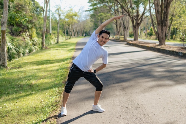 Jeune homme asiatique faisant des exercices d'étirement se préparant à courir dans la nature Mode de vie sain