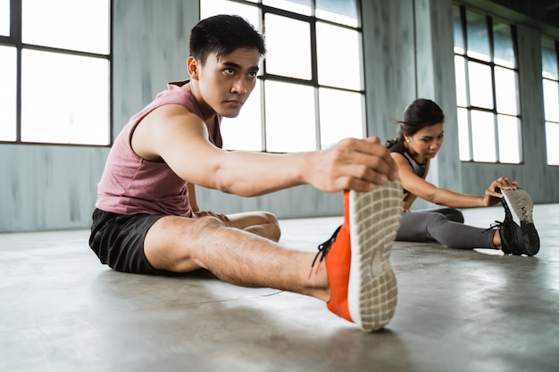 Jeune homme asiatique faisant des jambes qui s'étend avant l'exercice de base